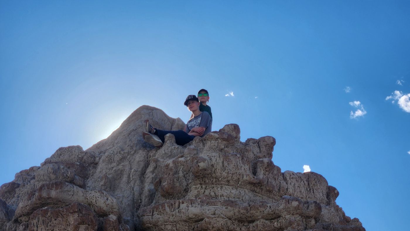 One of the boys perched high on a Badlands rock spire against the sky