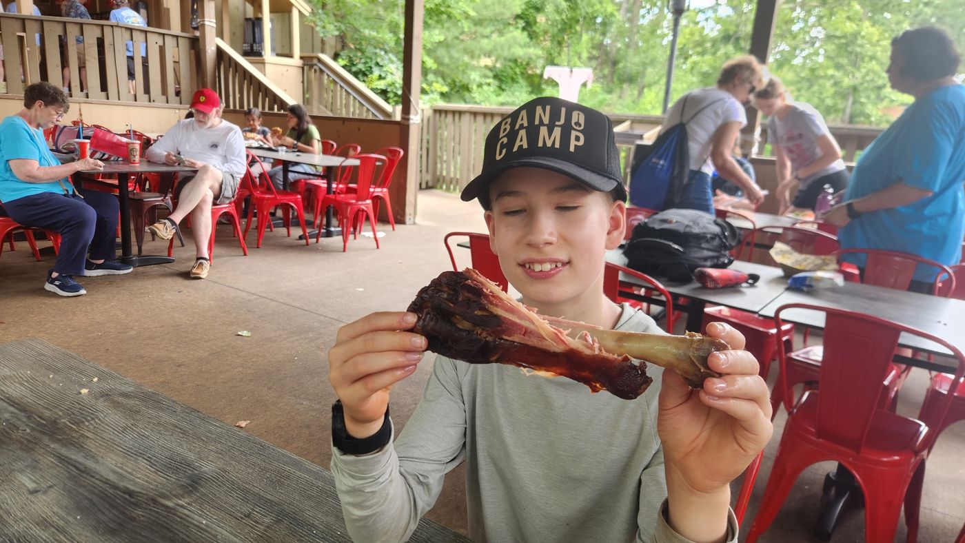 A boy in the Banjo Camp hat contemplating an enormous smoked turkey leg at Silver Dollar City